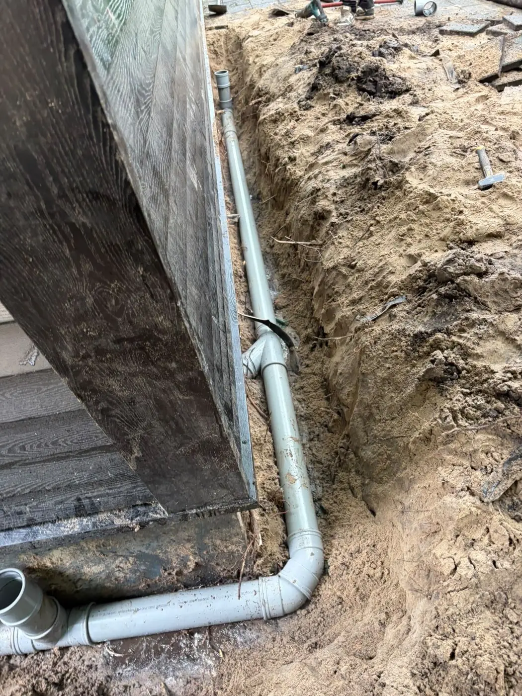 Nieuwe PVC-rioolleiding in een sleuf langs de gevel