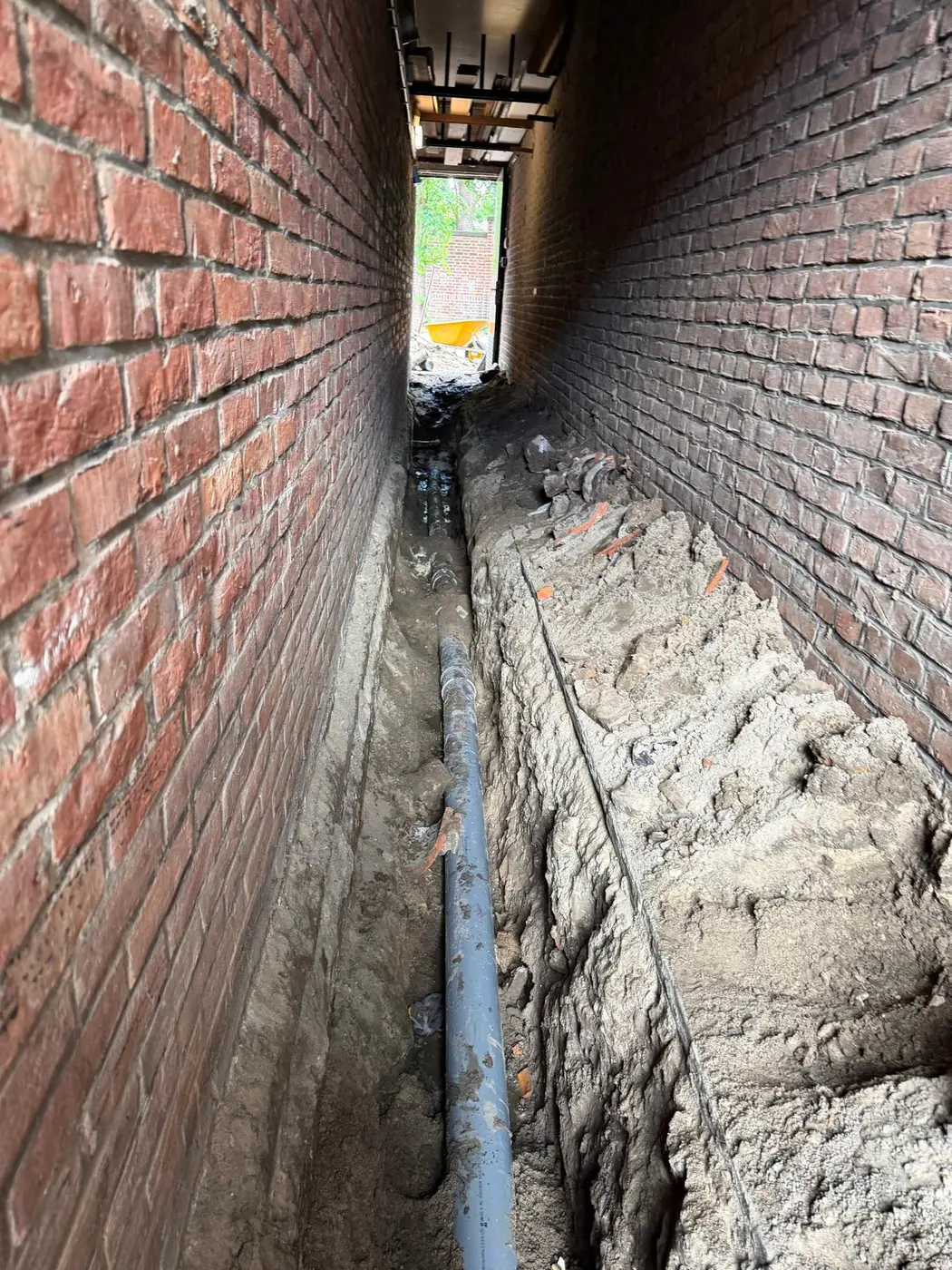Nieuwe rioolleiding in een uitgegraven doorgang tussen woningen